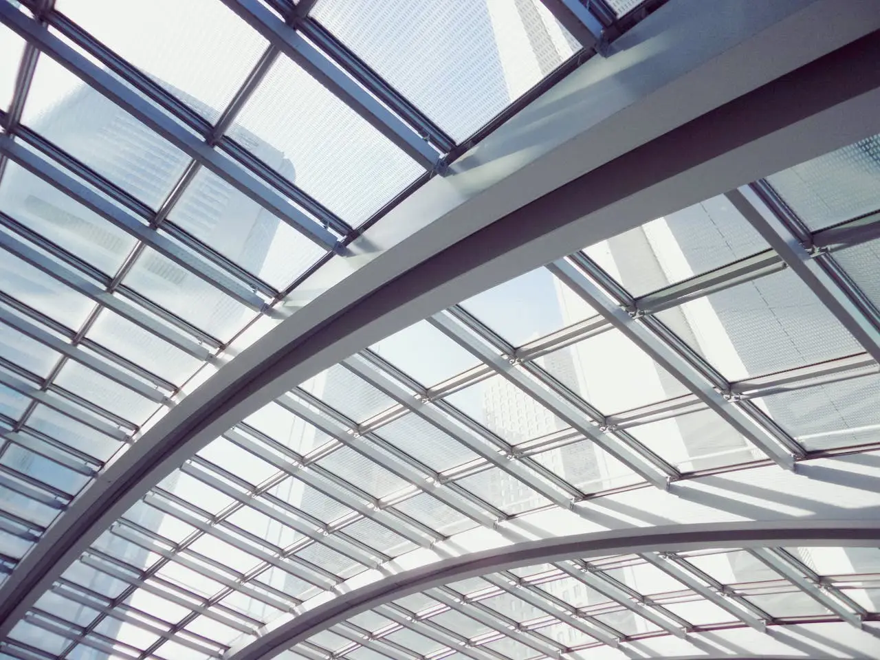 Interior shot of a modern glass ceiling featuring steel arches and geometric design elements.