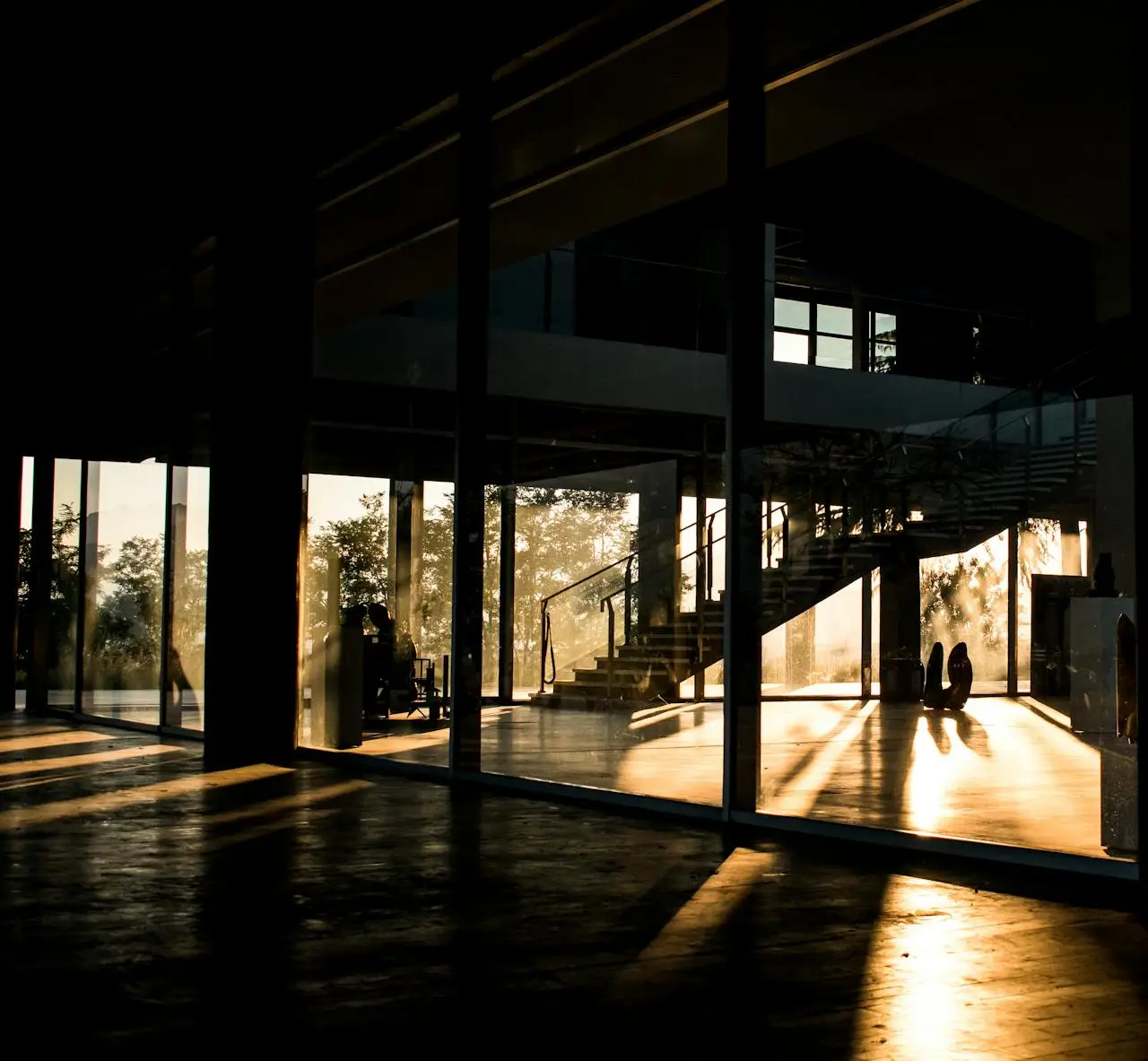 A modern building interior with sunlit reflections through large glass windows and stairs.